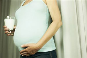 Беременная женщина держит стакан молока