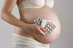 Беременная женщина держит таблетки