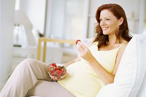 Беременная девушка ест клубнику