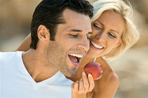 Девушка кормит мужчину яблоком