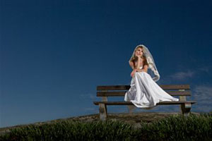 Девушка в свадебном платье сидит на лавке