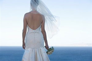 Девушка в свадебном платье стоит на обрыве