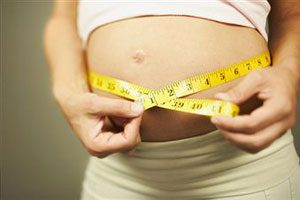 Беременная девушка измеряет свой живот