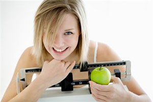 Девушка с яблоком в руках сидит на диете