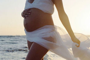 Беременная девушка гуляет по пляжу