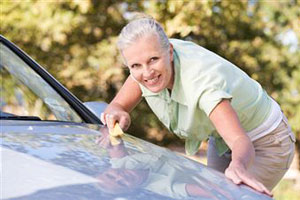 Женщина пытается отполировать свой автомобиль