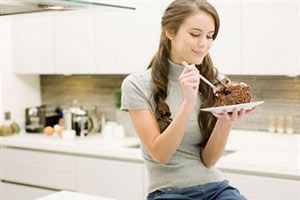 Девушка ест торт сидя на кухне