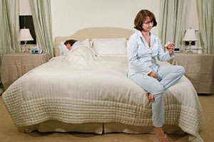 Женщина сидит на краю кровати