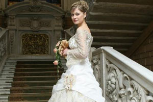 Девушка стоит на лестнице в зимнем свадебном платье