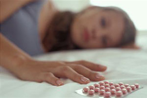 Девушка лежит на кровати около противозачаточного средства
