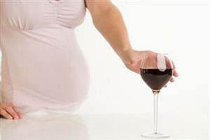 Бокал вина в руках у беременной девушки