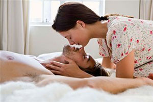 Девушка целует парня на кровате