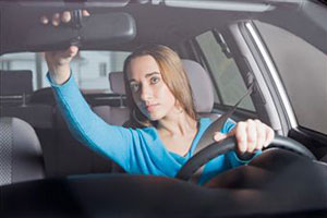 Женщина за рулем смотрит в зеркало