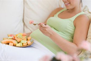 Беременная девушка ест фрукты