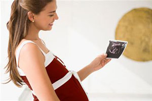 Беременная женщина смотрит на снимок УЗИ