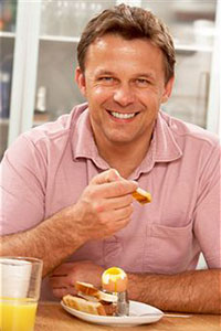 Мужчина ест яйцо