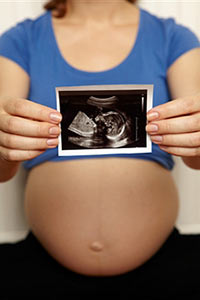Беременная женщина держит снимок УЗИ